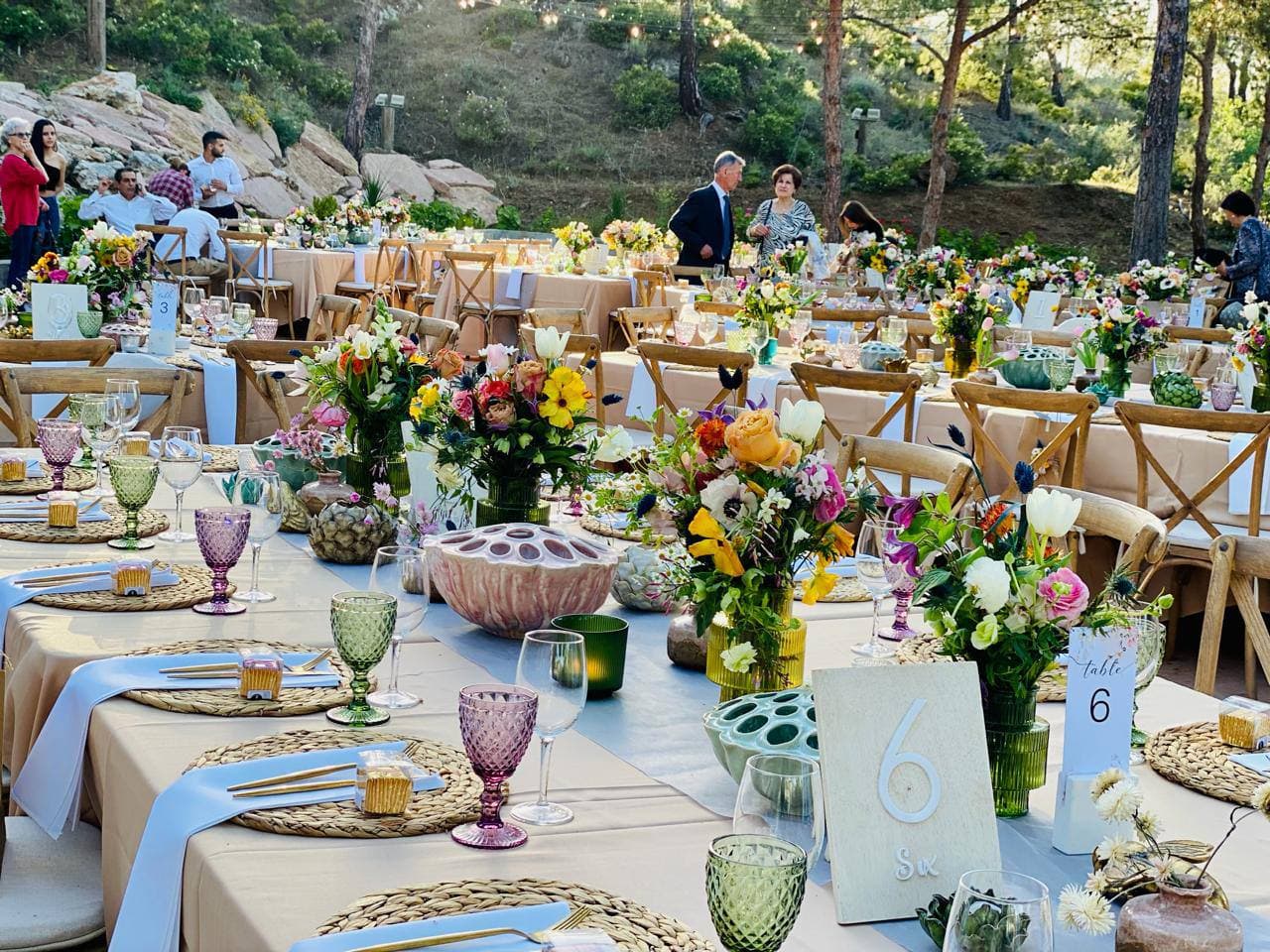 Guests arriving at long tables laid for lunch in the afternoon sun